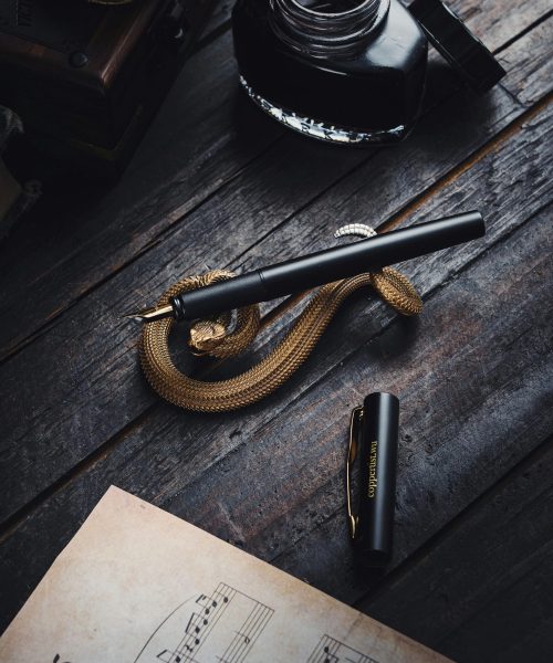 A sophisticated fountain pen rests on vintage sheet music beside an ink bottle, creating a timeless writing scene.